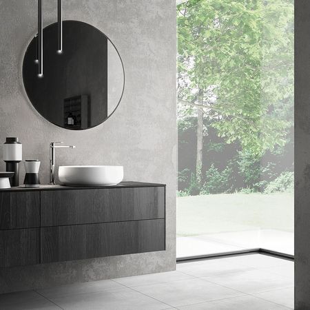 Stylisches Badezimmer mit Waschbecken und rundem Spiegel vor Fensterfront